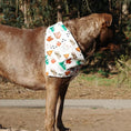 Load image into Gallery viewer, Brown dog wearing a white bandana with camping print featuring tents, trees, and paw prints